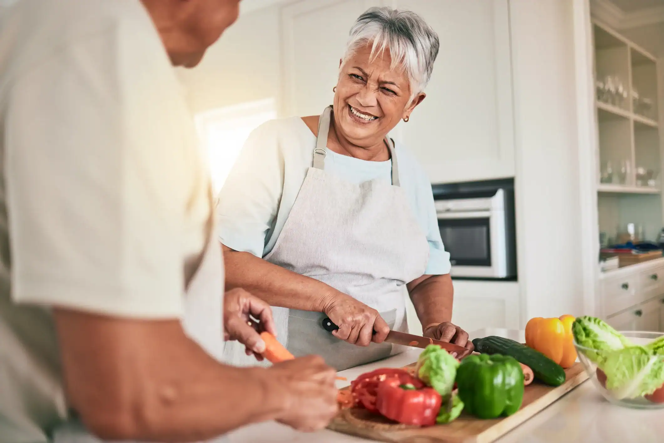 happy older women cutting vegetables